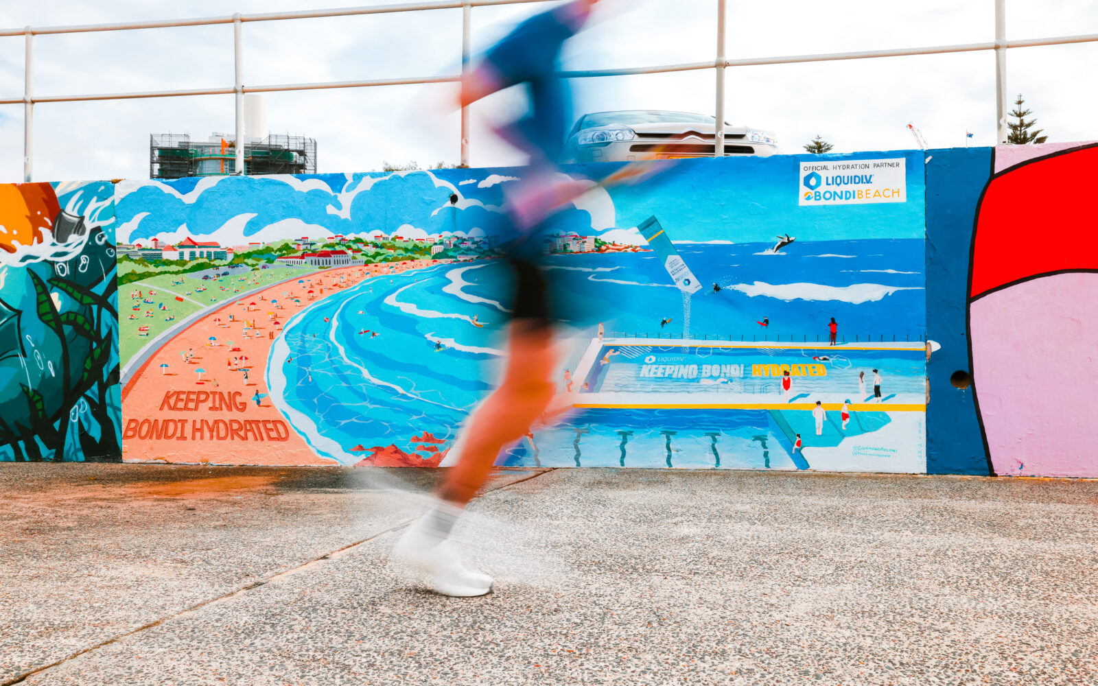 011A3731 Man running infront of a Liquid IV advert at Bondi Beach.